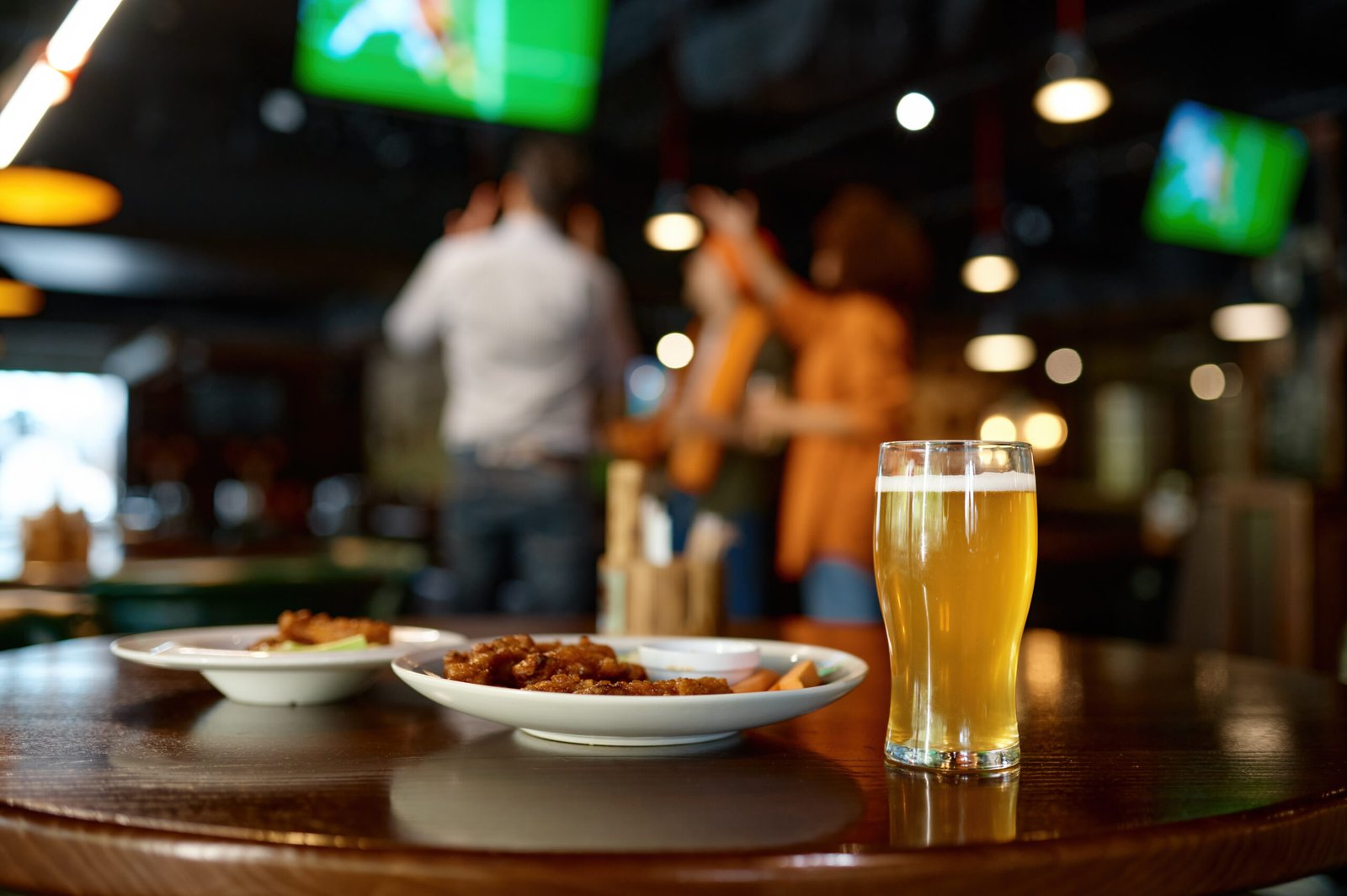 Beer and food spread on a table in a sports bar setting at Black Harbor Brewing